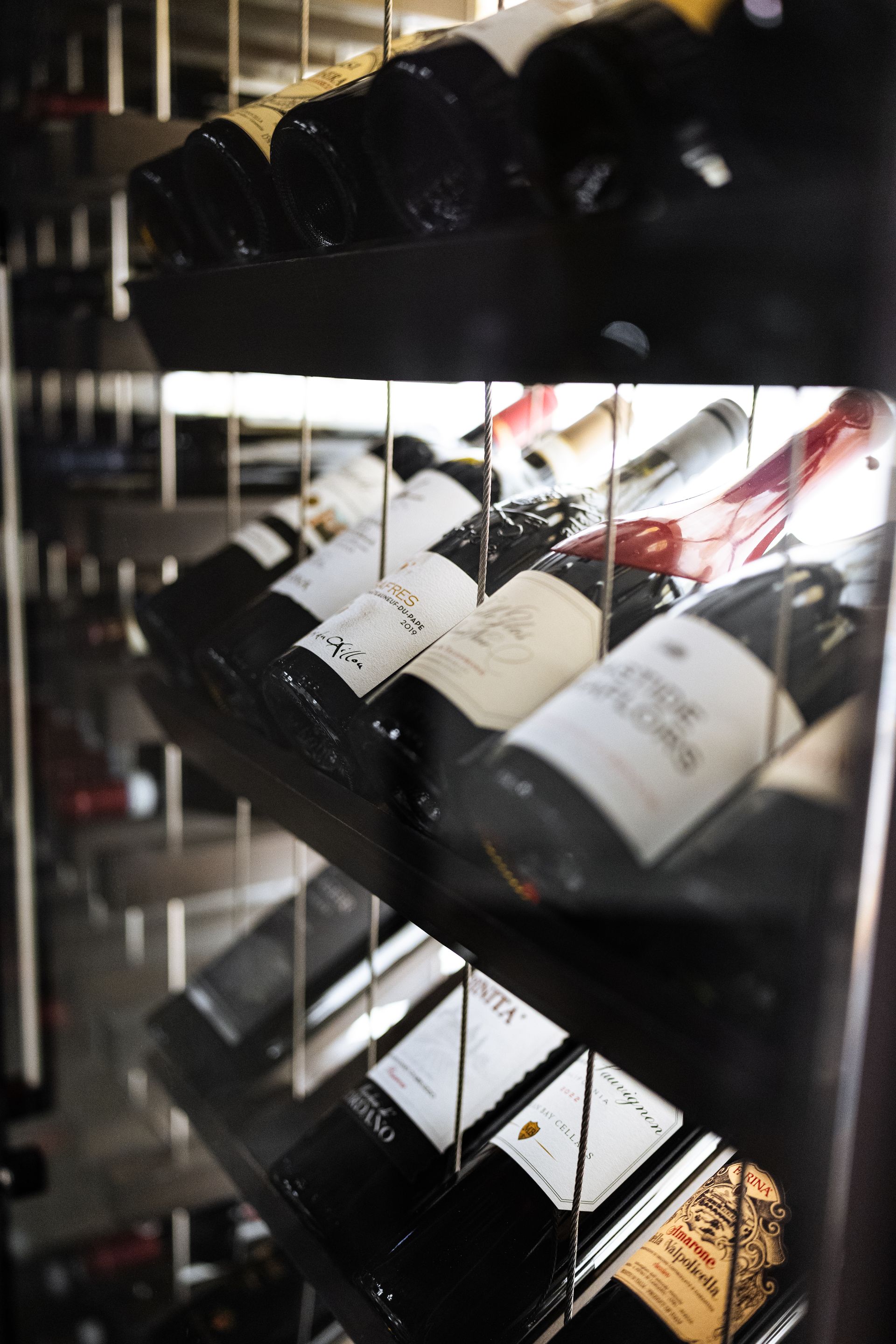 Several bottles of wine are lined up on a shelf in a wine cellar.