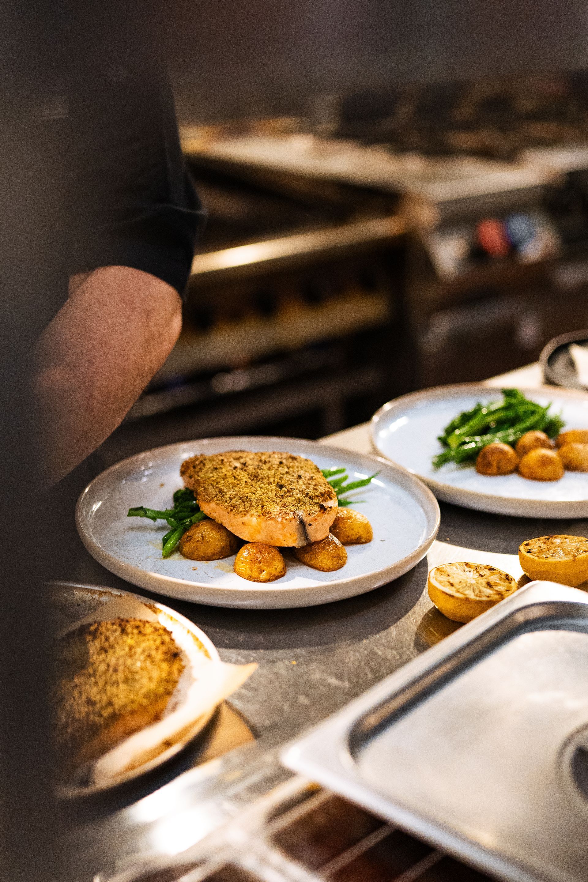 A chef is preparing plates of food in a kitchen.