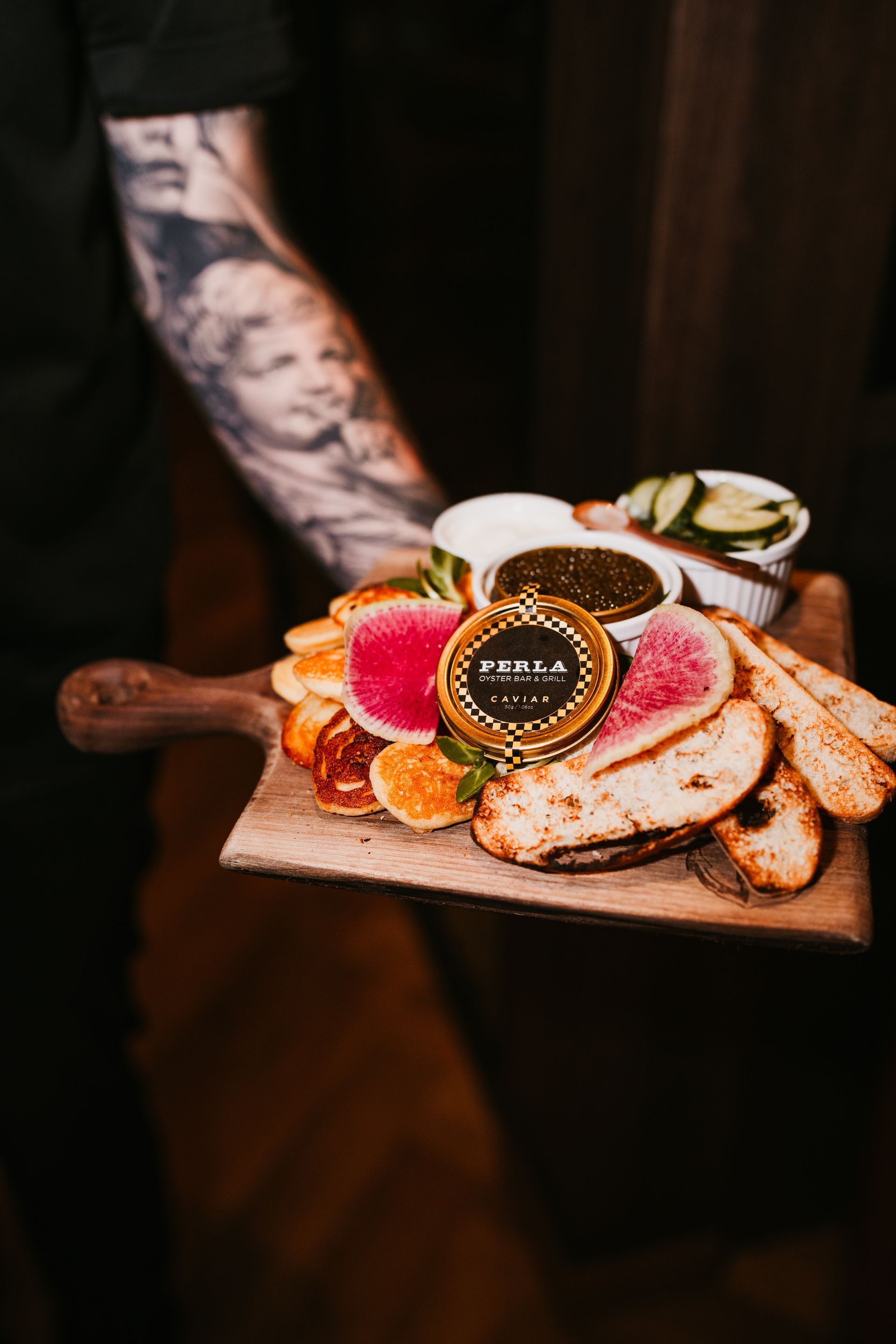 A man is holding a wooden cutting board with food on it.