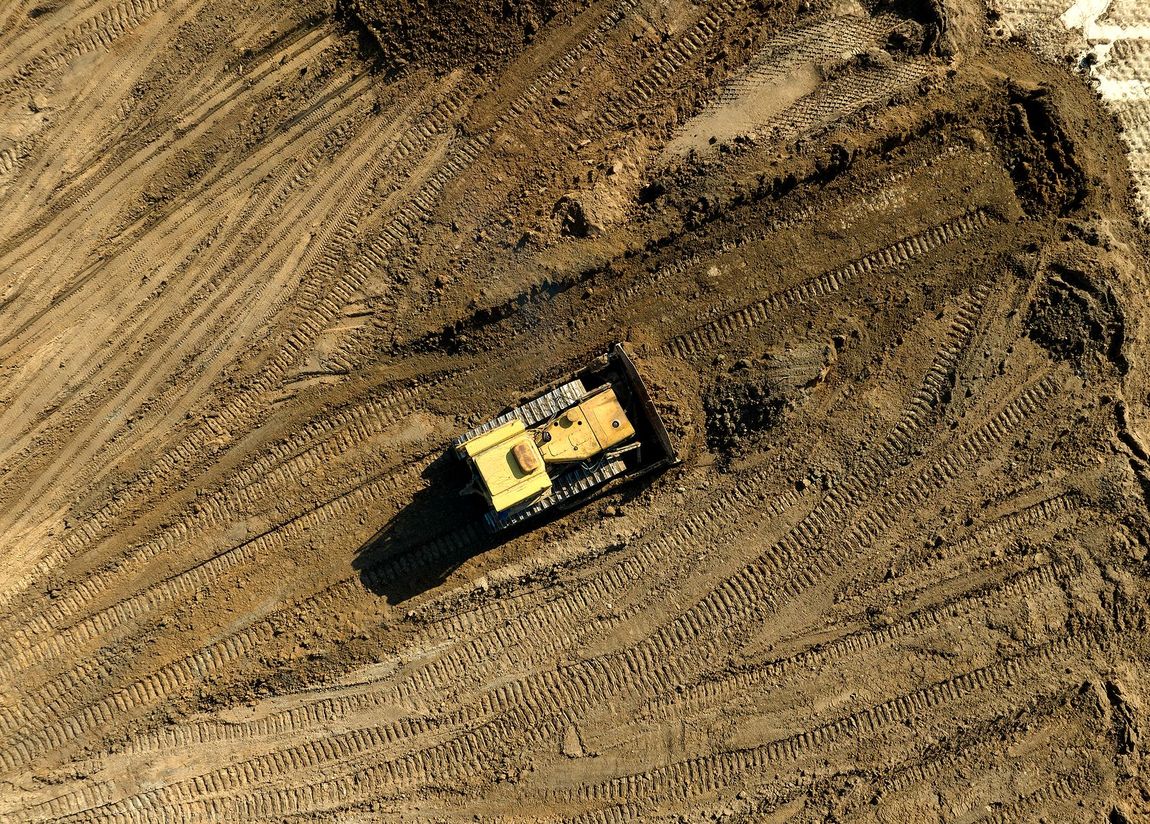 An aerial view of a bulldozer moving dirt in a field.