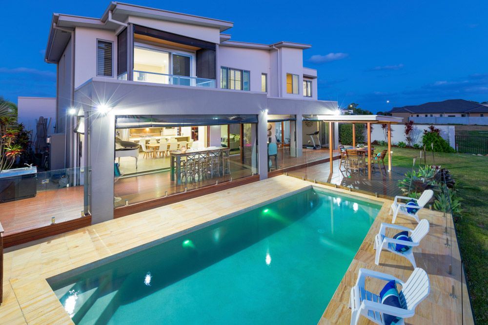 A Large House With A Large Swimming Pool In Front Of It — Glenn Merrick Constructions In Bowen, QLD