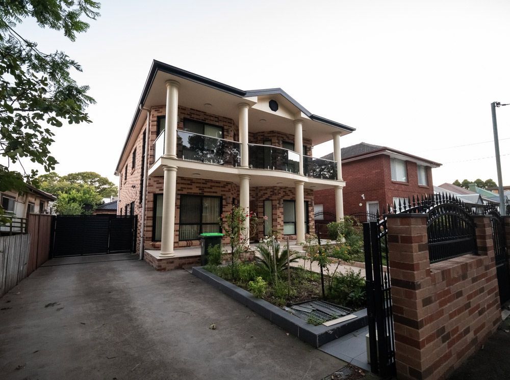 A Large Brick House With Columns And Balconies — Glenn Merrick Constructions In Collinsville, QLD