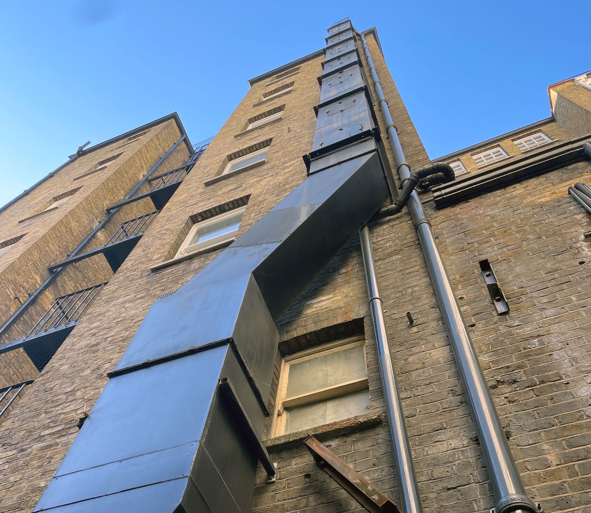 Looking up at a tall brick building with a fire escape