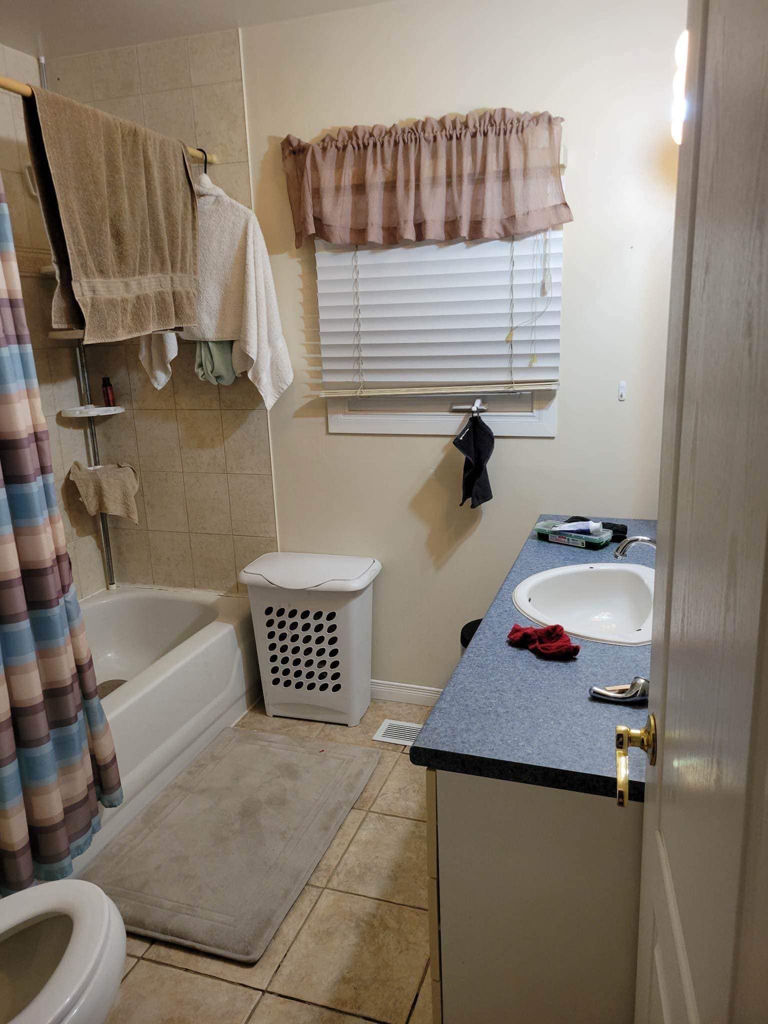 Une salle de bain avec lavabo, WC, baignoire et fenêtre.