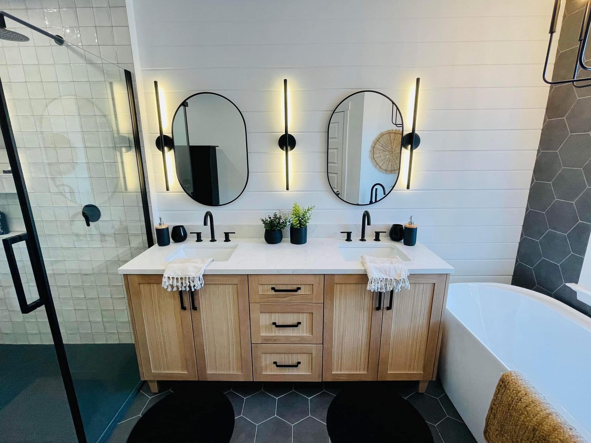 Une salle de bain avec deux lavabos, deux miroirs et une baignoire.