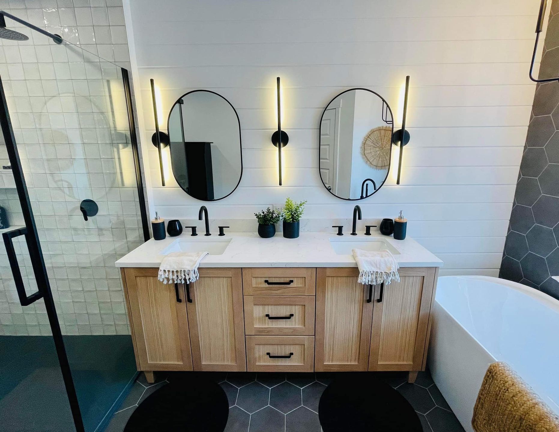 Une salle de bain avec deux lavabos, deux miroirs et une baignoire.