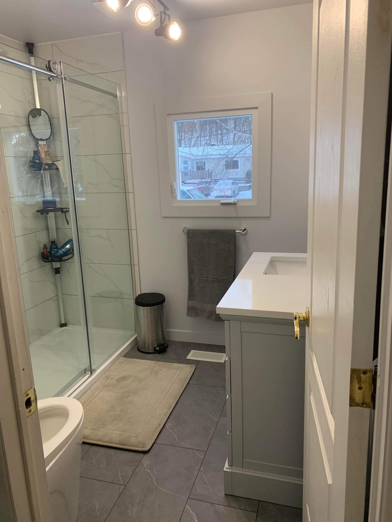 Une salle de bain avec lavabo, WC, douche et fenêtre.