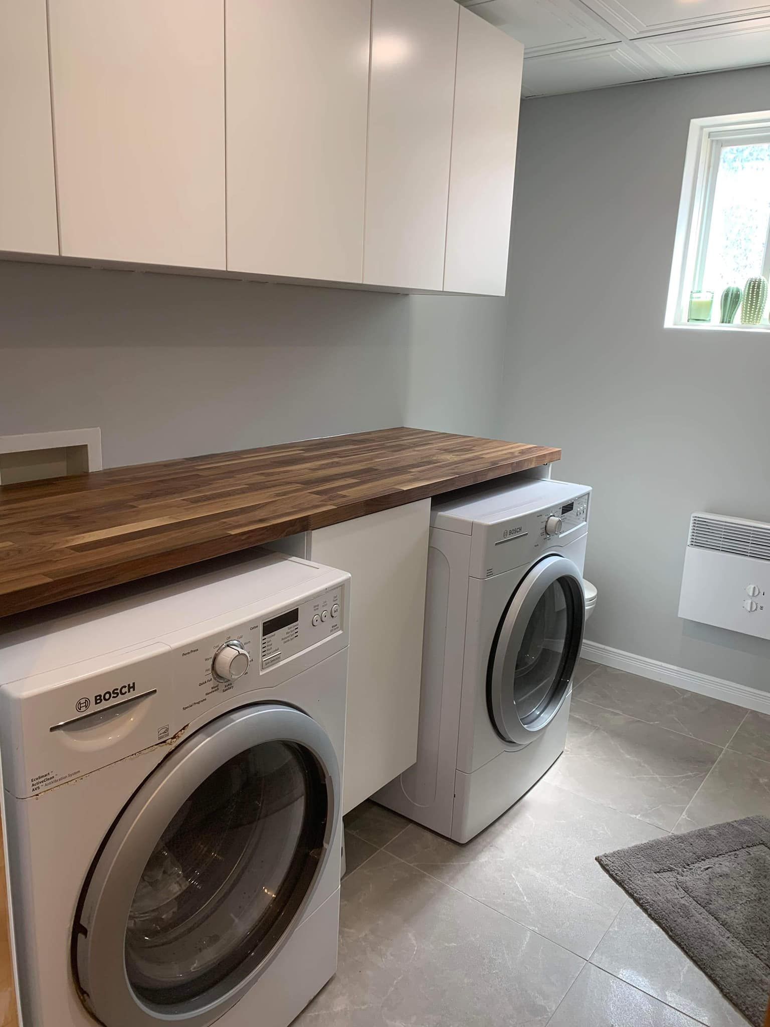 Une buanderie avec deux machines à laver et un plan de travail en bois.