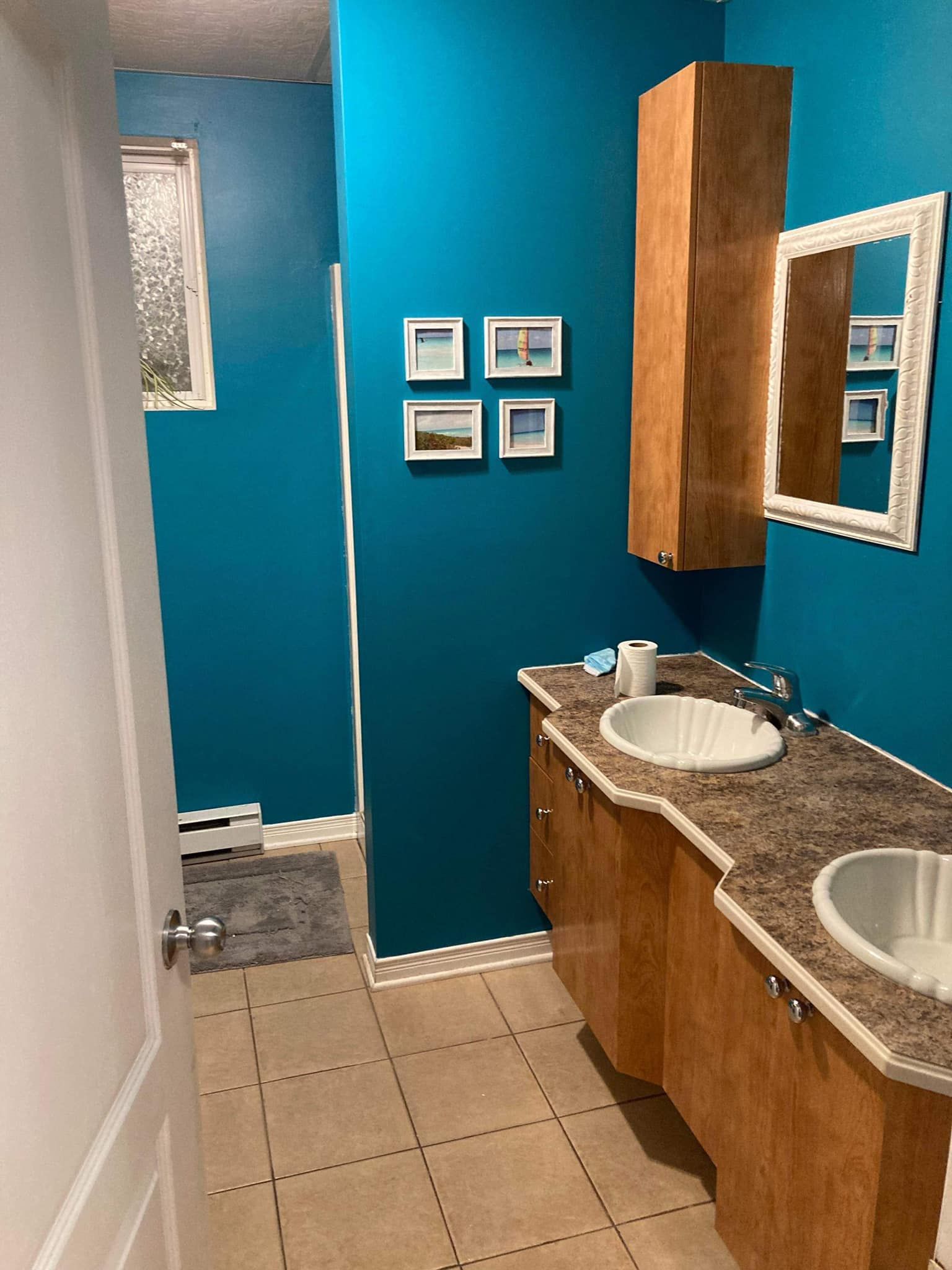 Une salle de bain avec deux lavabos, un miroir et des murs bleus.