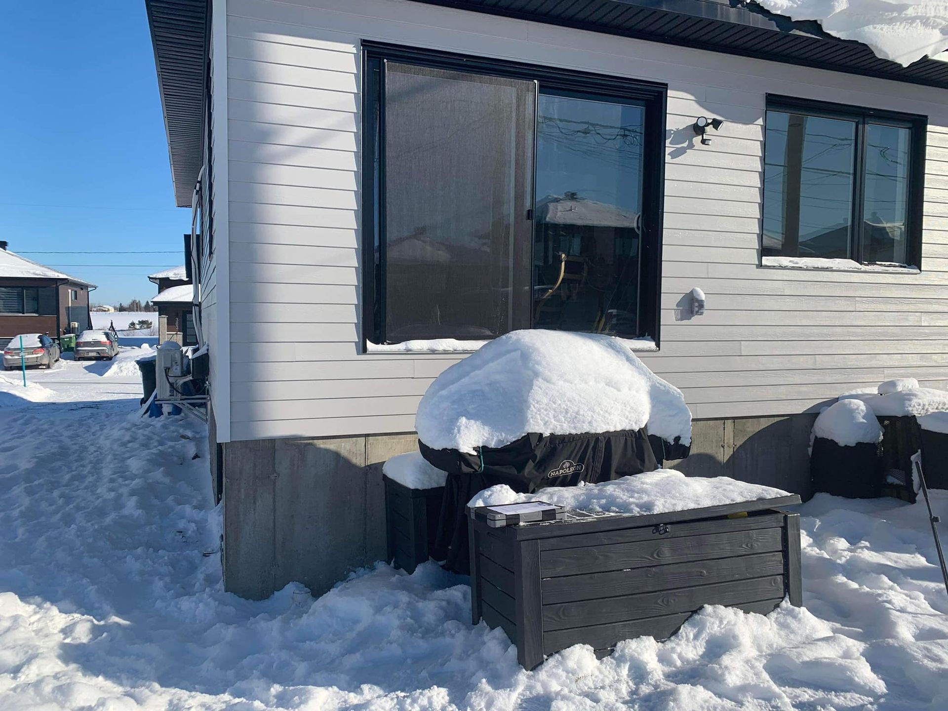 Une maison couverte de neige avec un jacuzzi devant