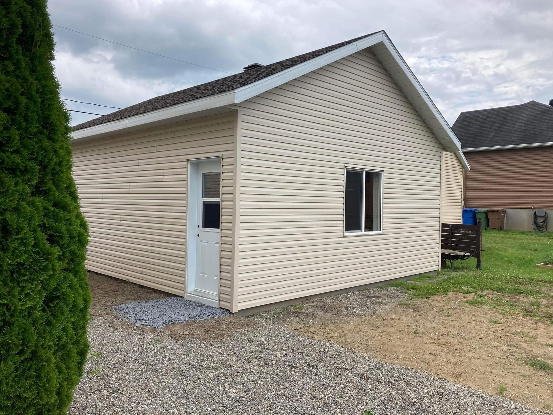 Une petite maison avec un revêtement blanc et une porte blanche.