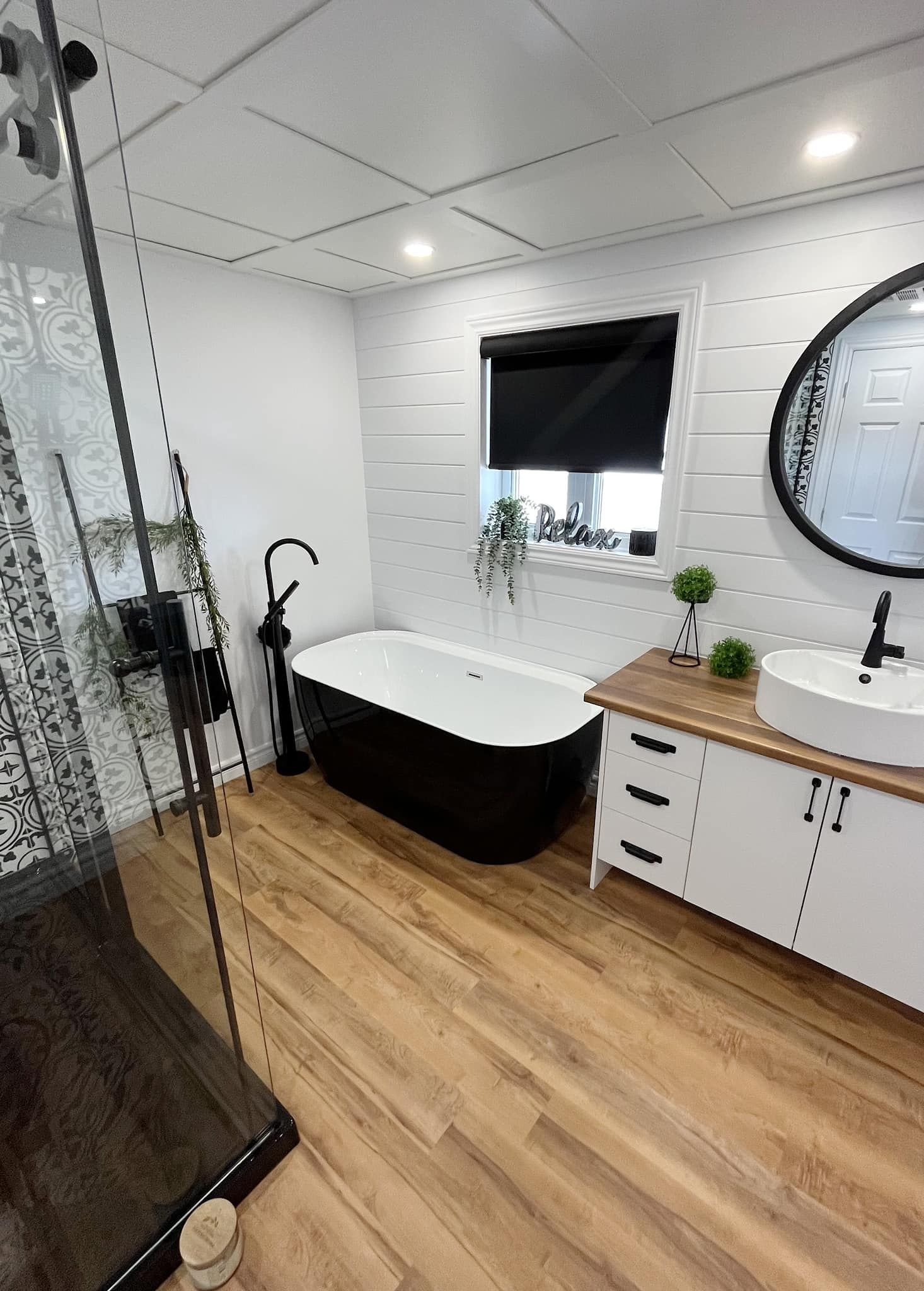 Une salle de bain avec baignoire noire, lavabo, miroir et douche.