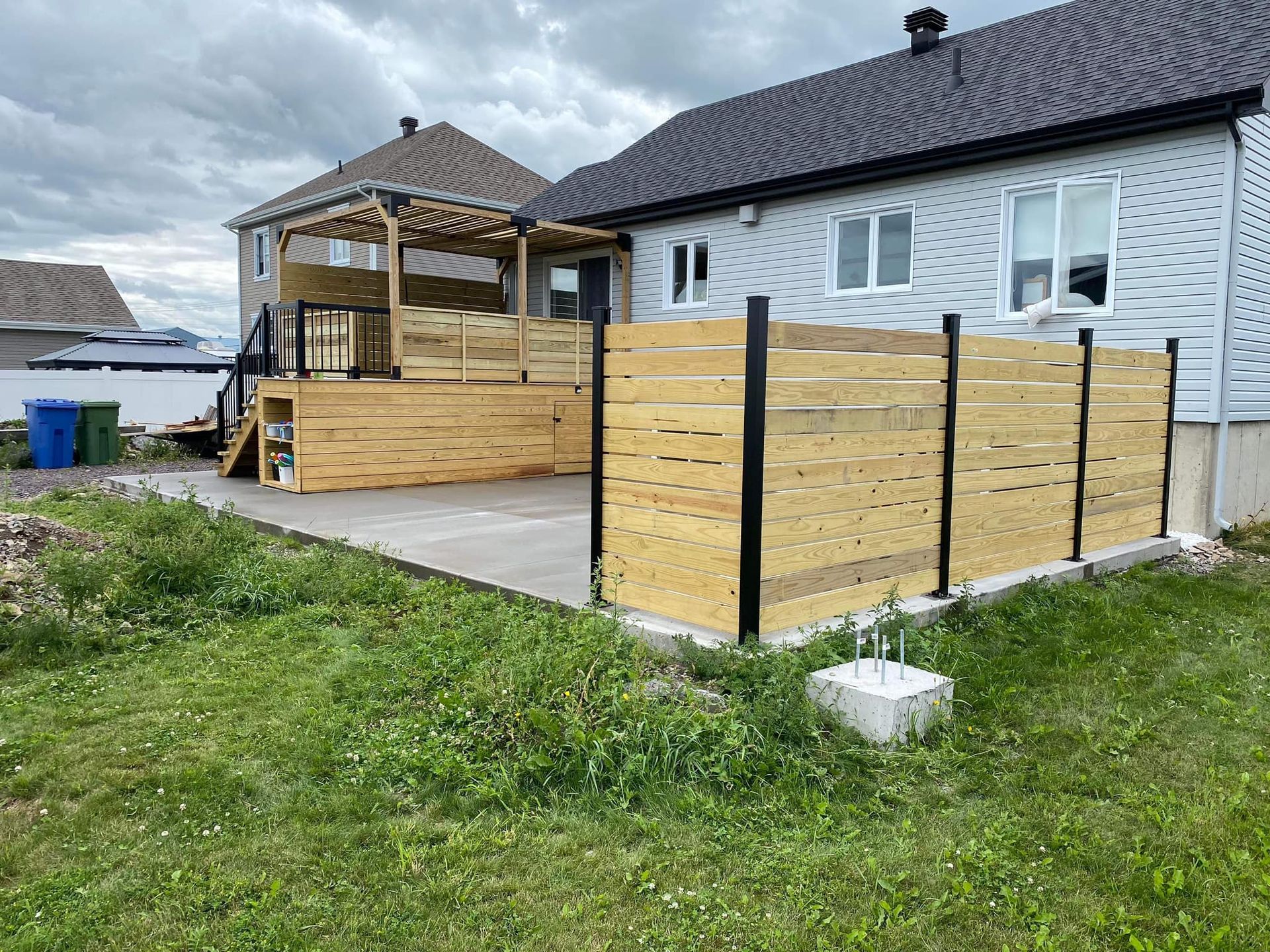 Une maison avec une terrasse en bois et une clôture en bois devant.