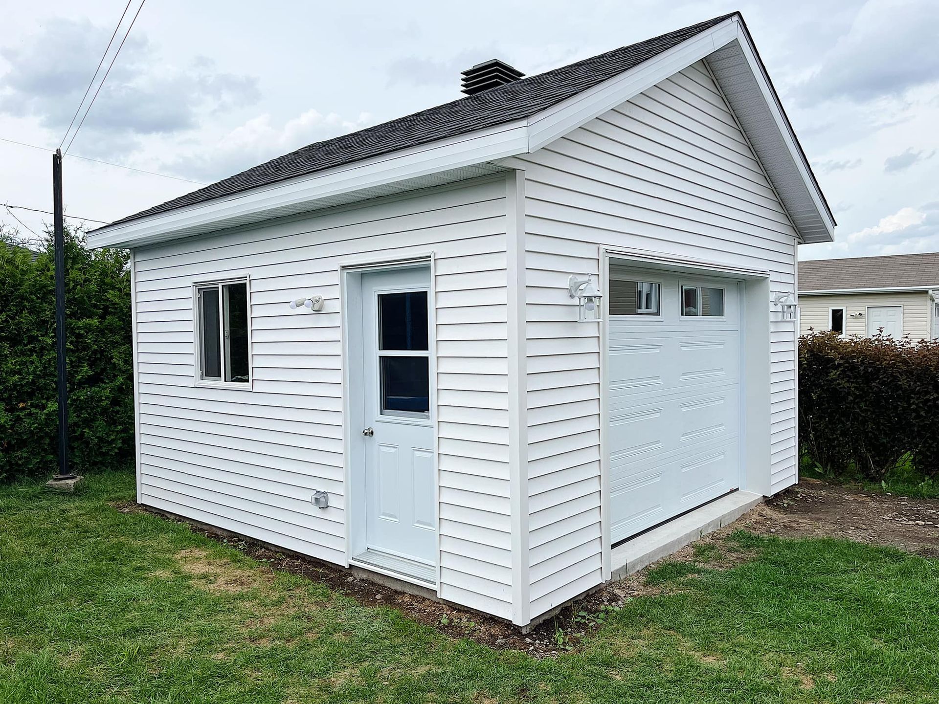 Un petit garage blanc avec une porte de garage et une fenêtre.