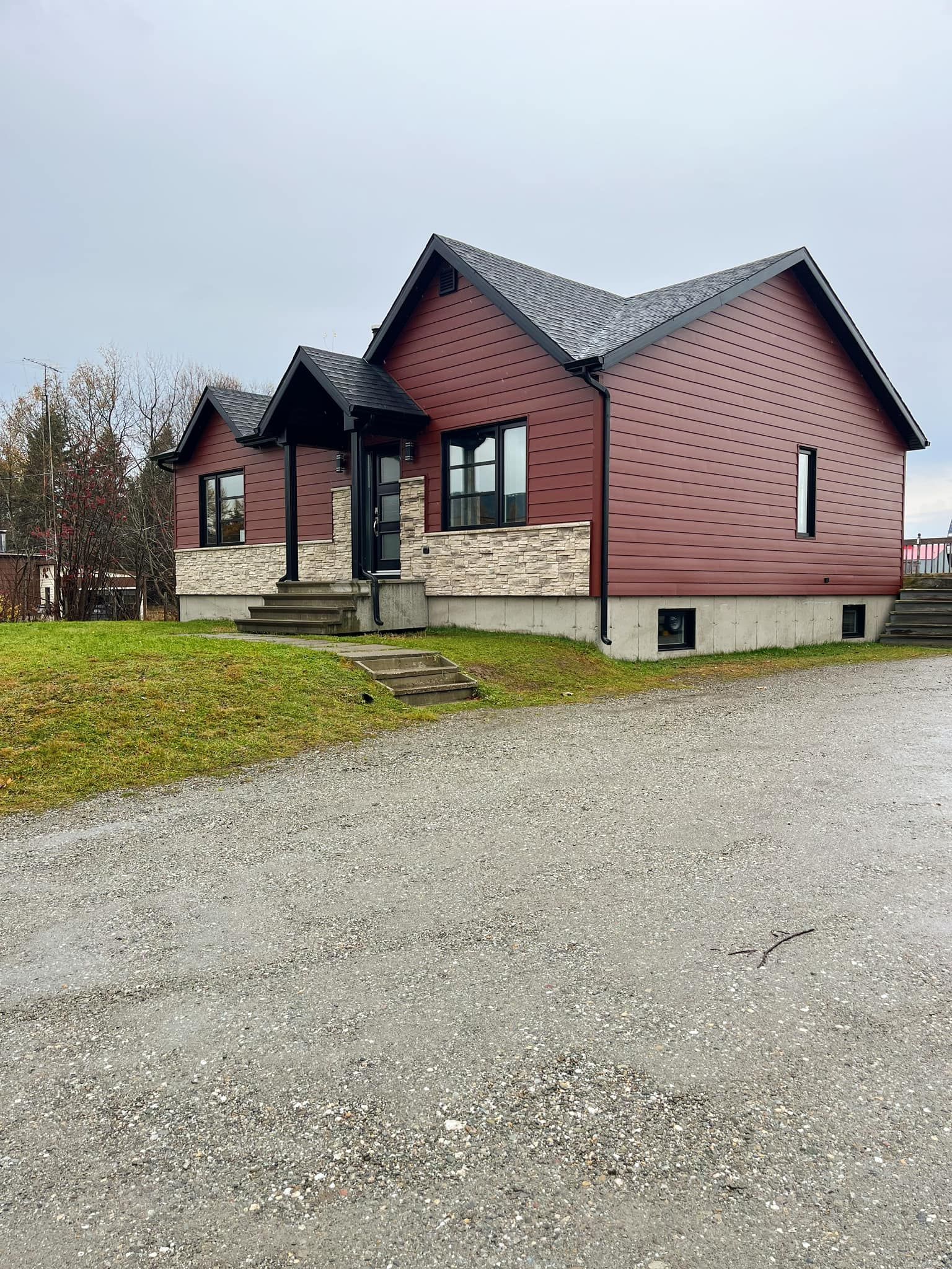 Une petite maison rouge avec une allée de gravier devant elle.