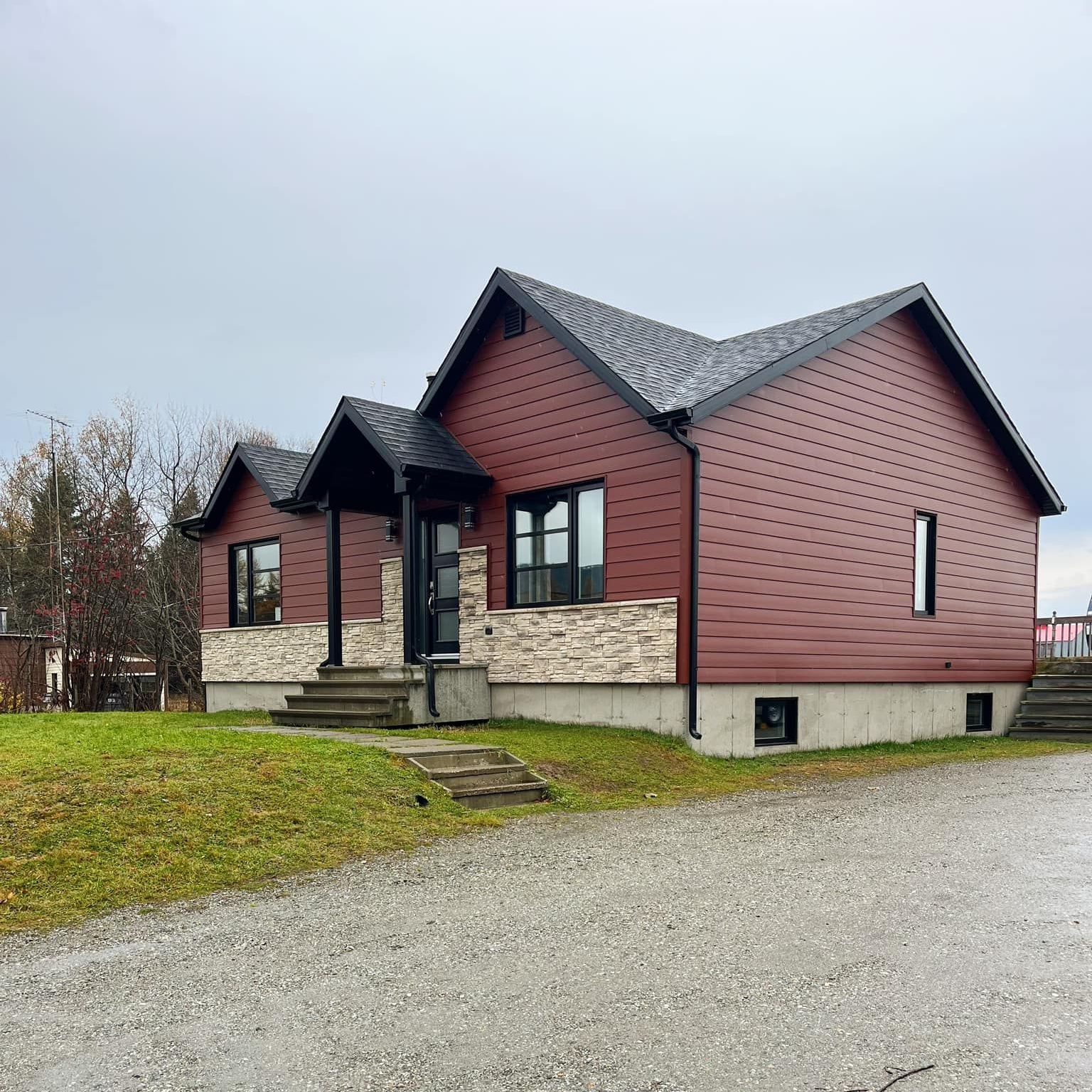 Une maison avec un revêtement rouge et un toit noir