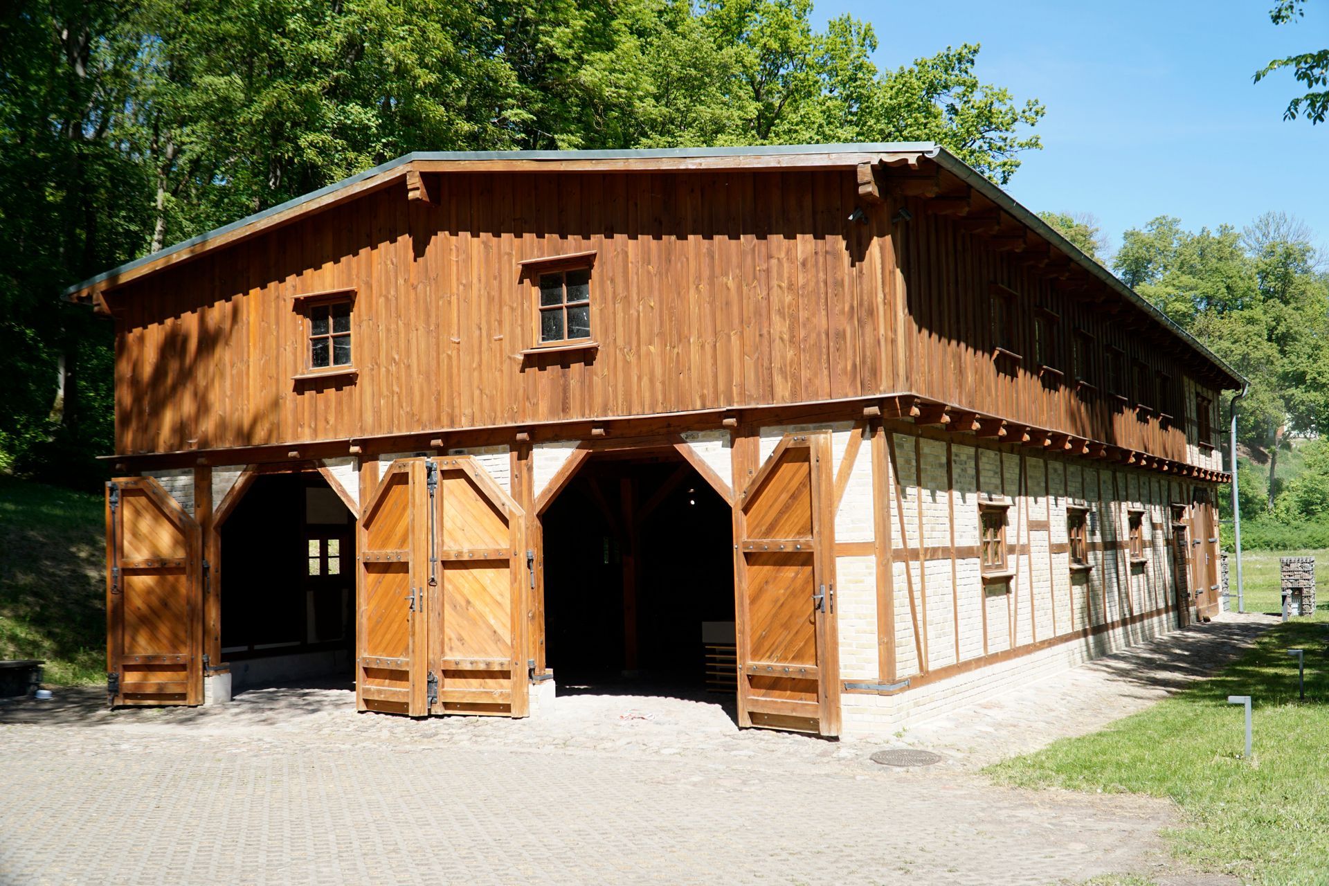Large two-story barn with wooden paneling and brick lower walls