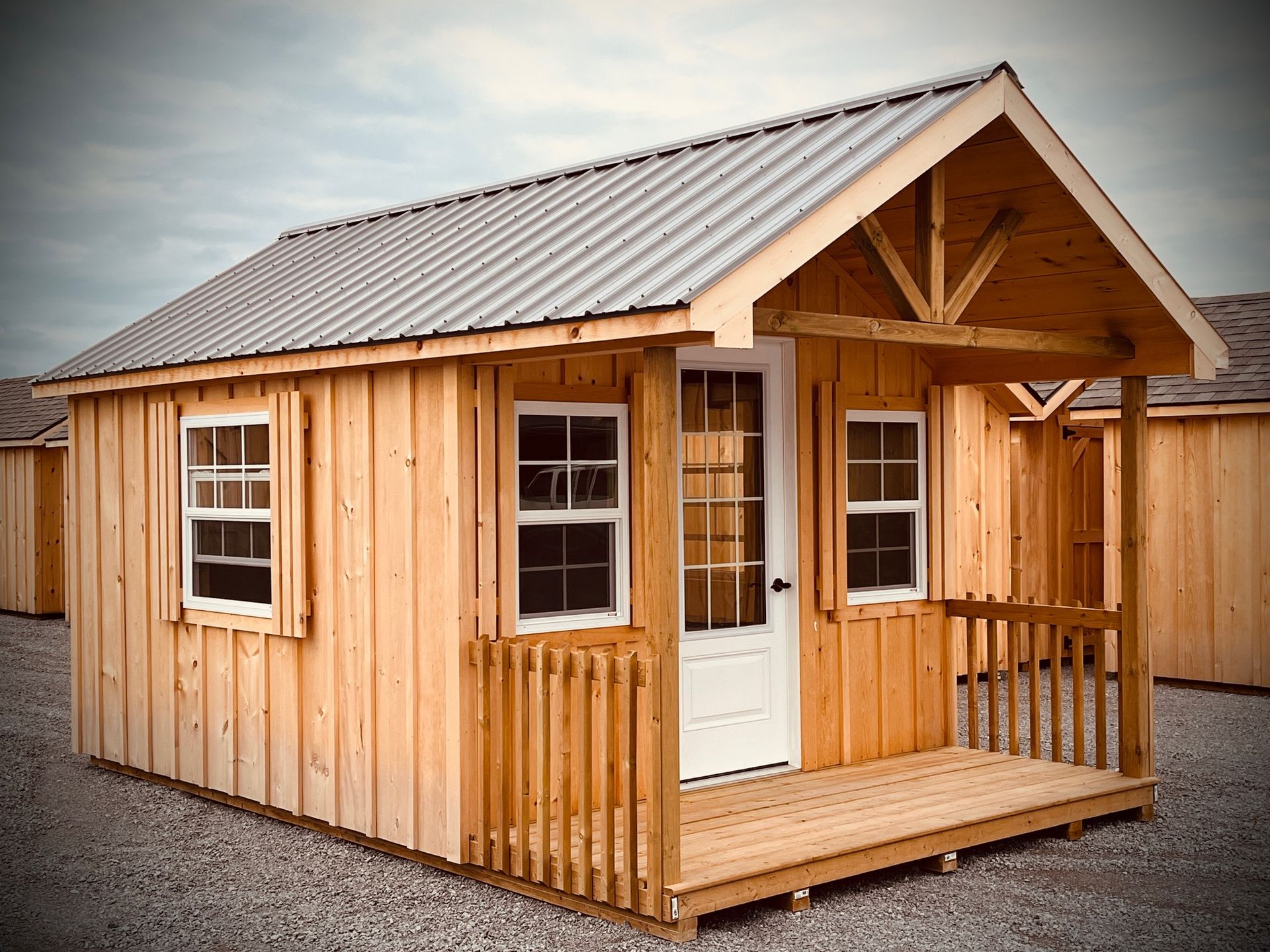 A small wooden shed with a porch and a metal roof.