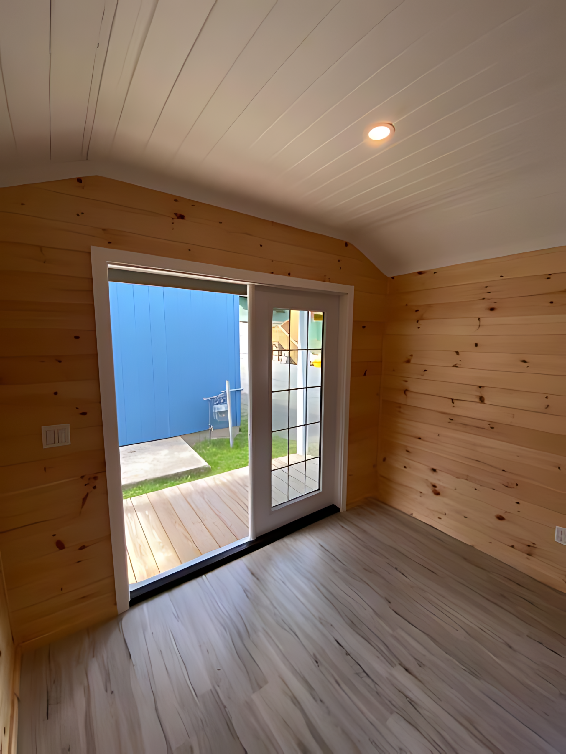 An empty room with a sliding glass door and wooden walls.