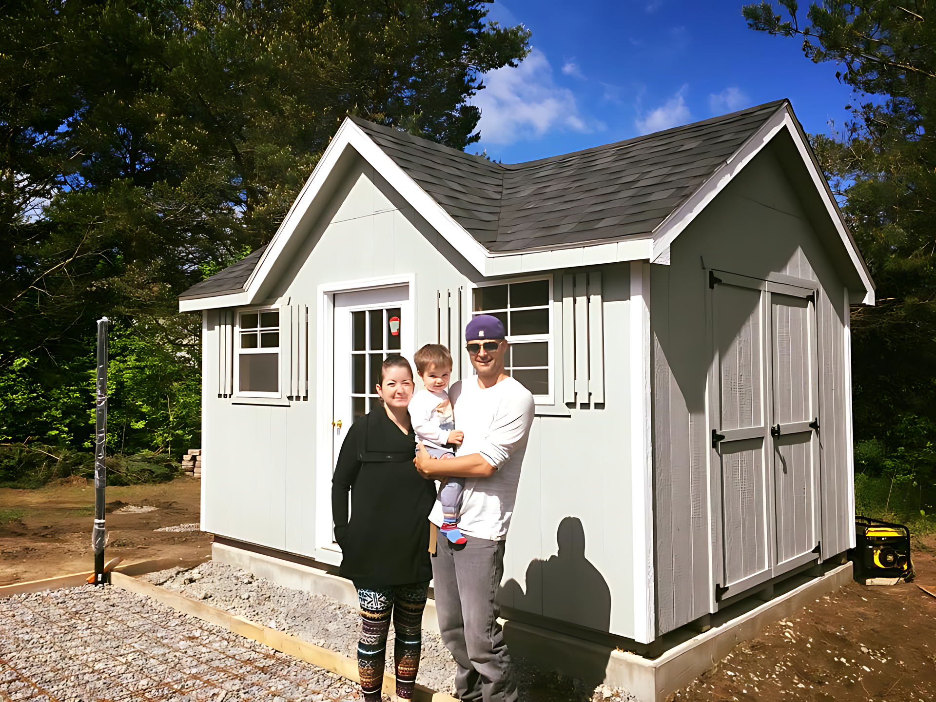 A family standing in front of a small white shed