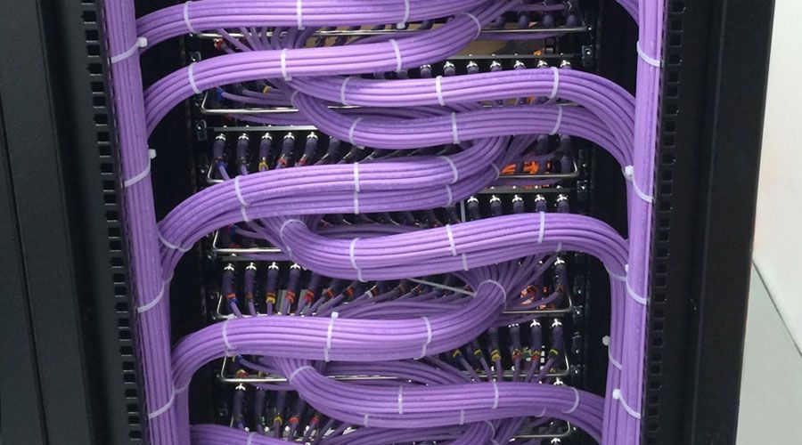 Un rack de servidores lleno de muchos cables morados.