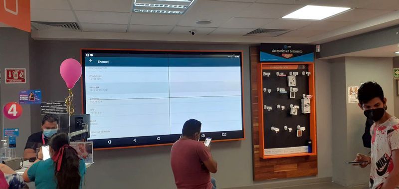 Un grupo de personas está de pie frente a una pantalla grande en una tienda.