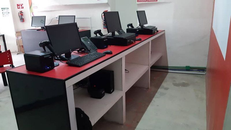 Una fila de computadoras colocadas encima de una mesa roja.
