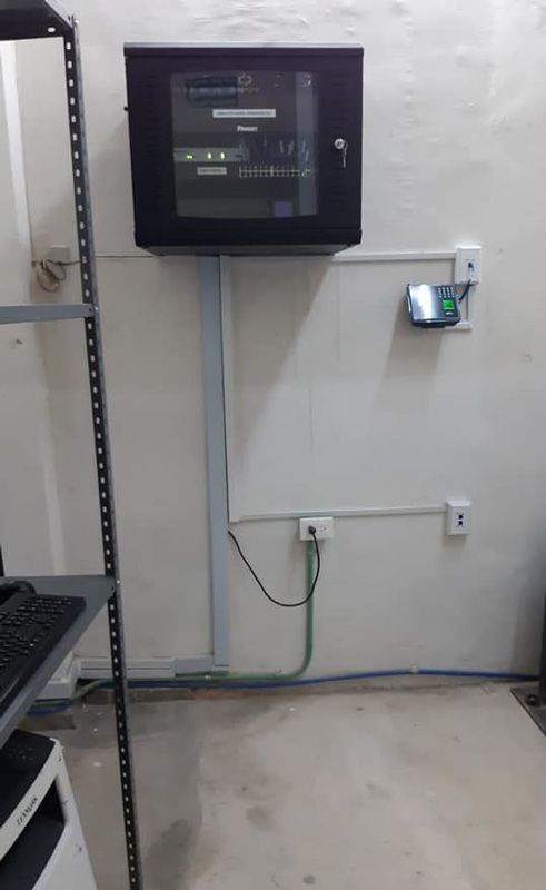 Un armario negro está colgado en una pared al lado de una impresora.