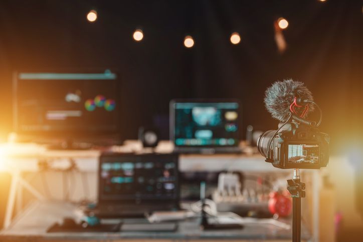 Un micrófono está colocado sobre un trípode delante de una computadora portátil.