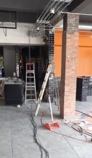 Una escalera está en el medio de una habitación al lado de una columna de ladrillo.