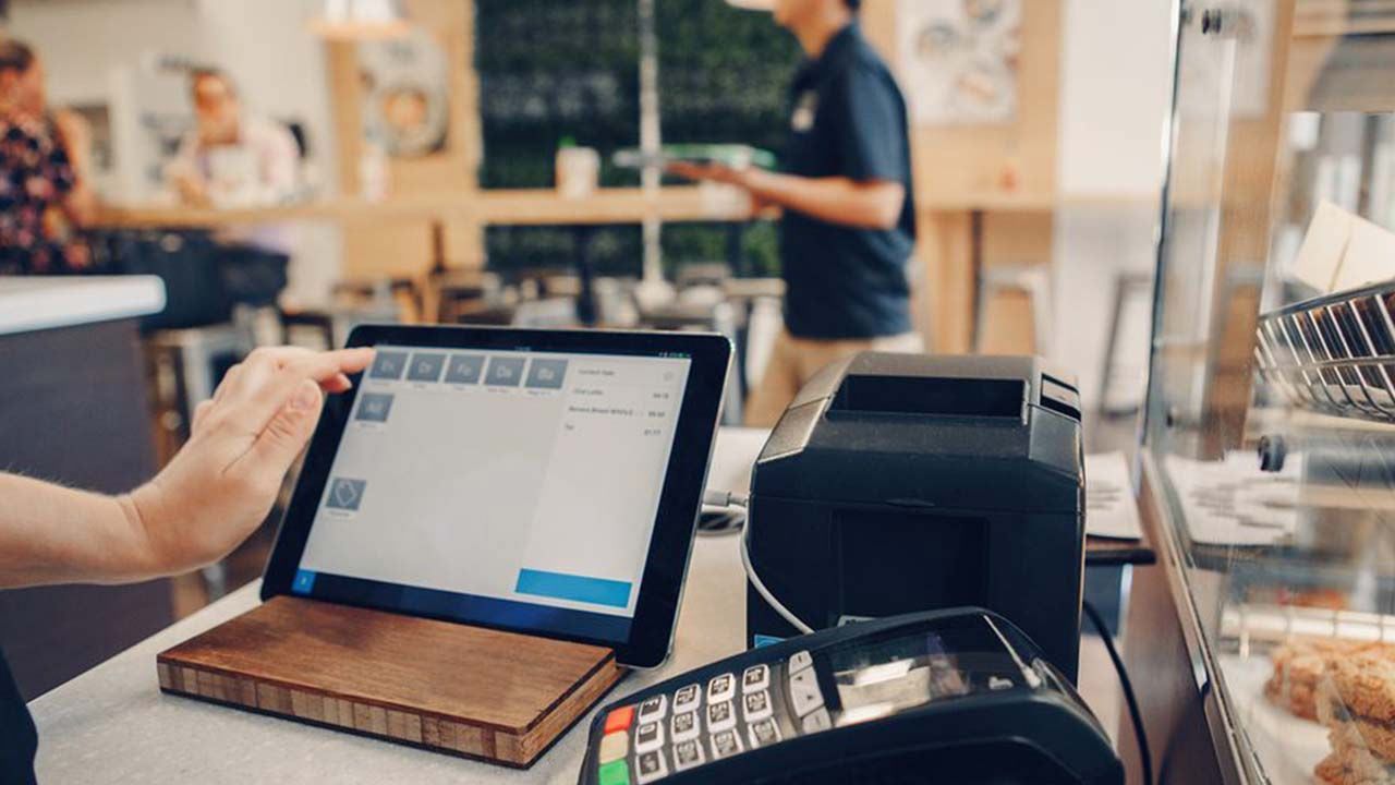 Una persona está usando una tableta para pagar algo en un restaurante.