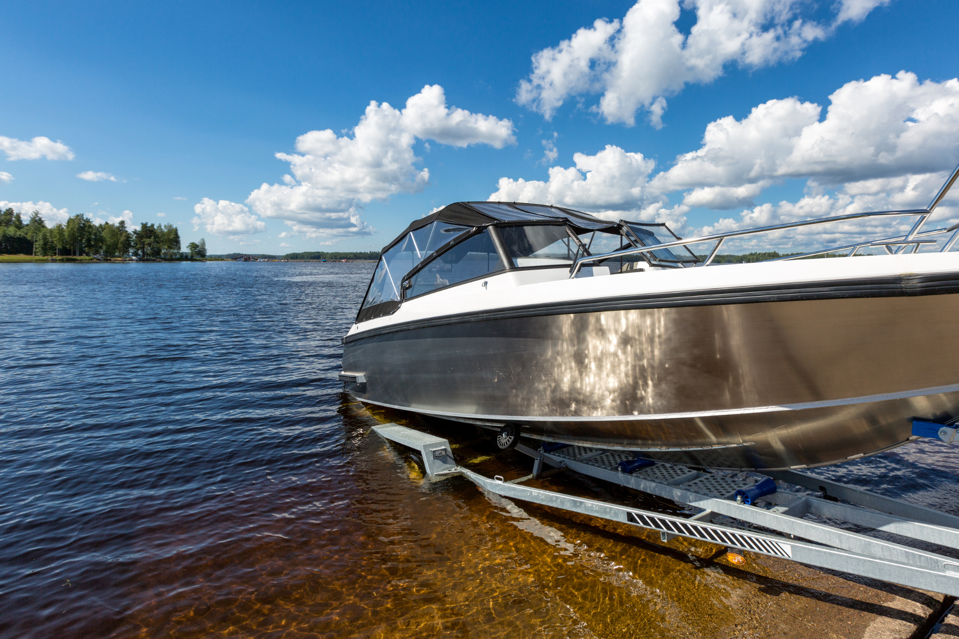A boat is being towed by a trailer in a parking lot.