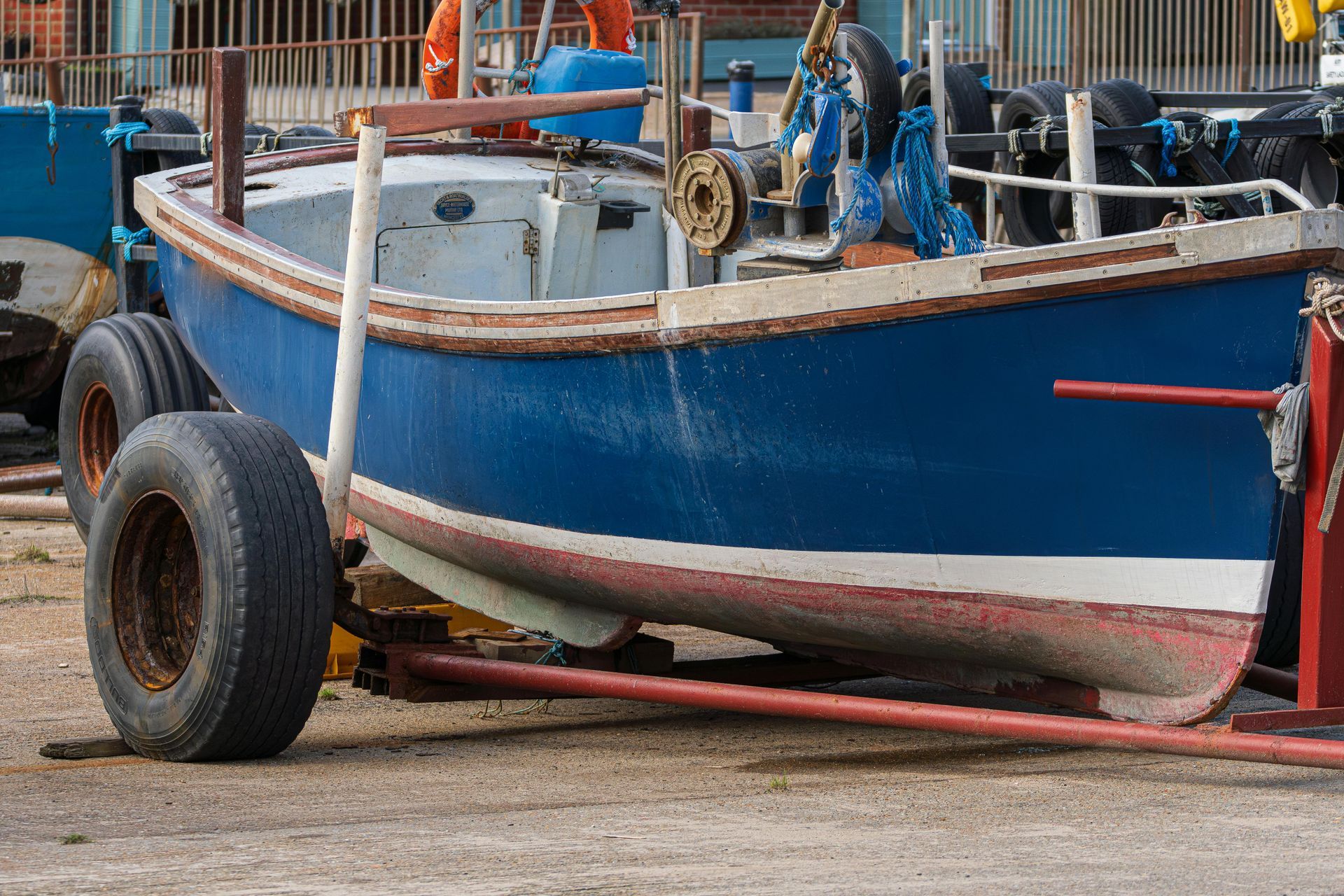A boat is being towed by a trailer in a parking lot.