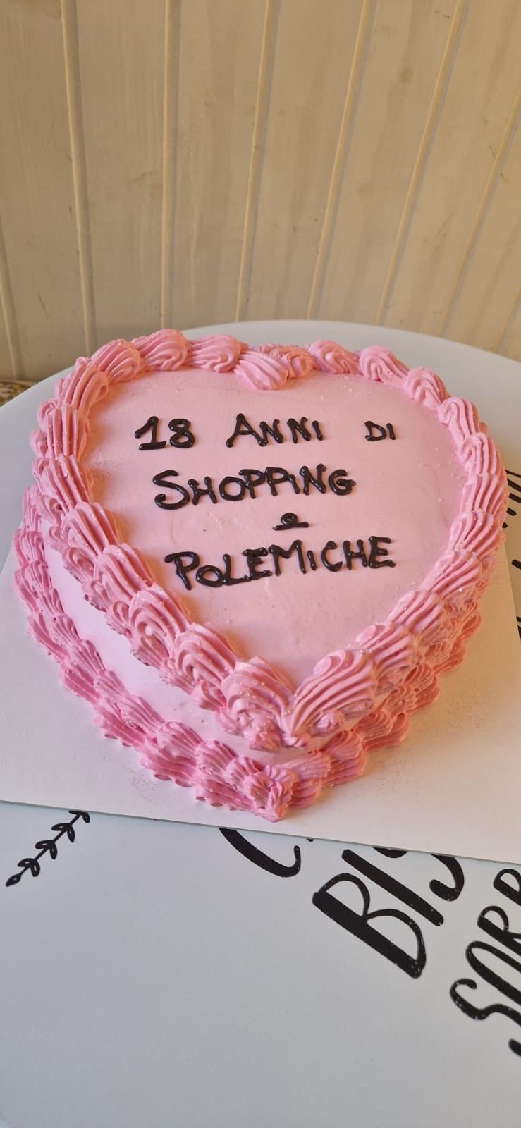 Torta rosa a forma di cuore con glassa nera. Sopra c'è scritto