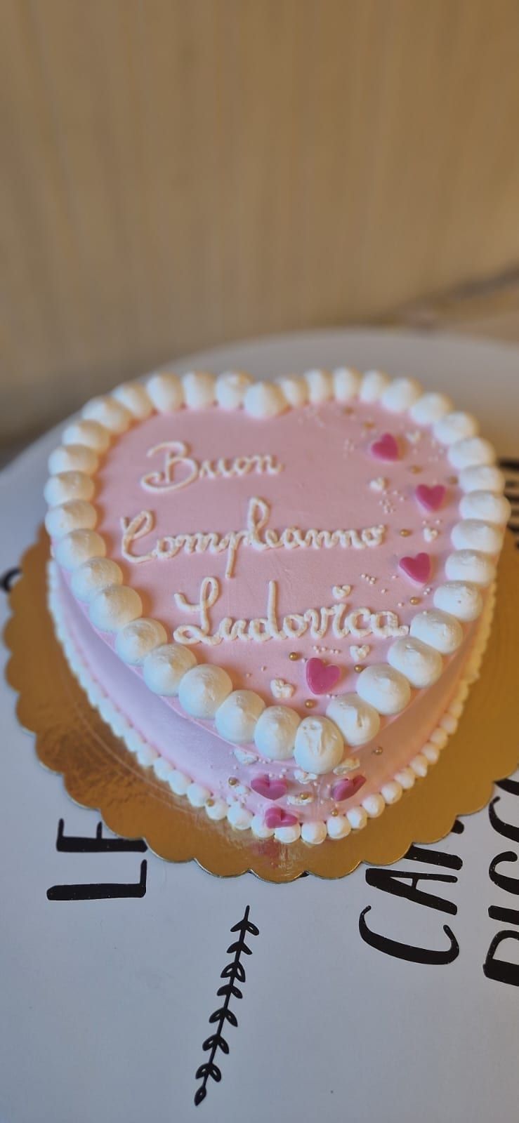 Torta rosa a forma di cuore con glassa bianca e la scritta