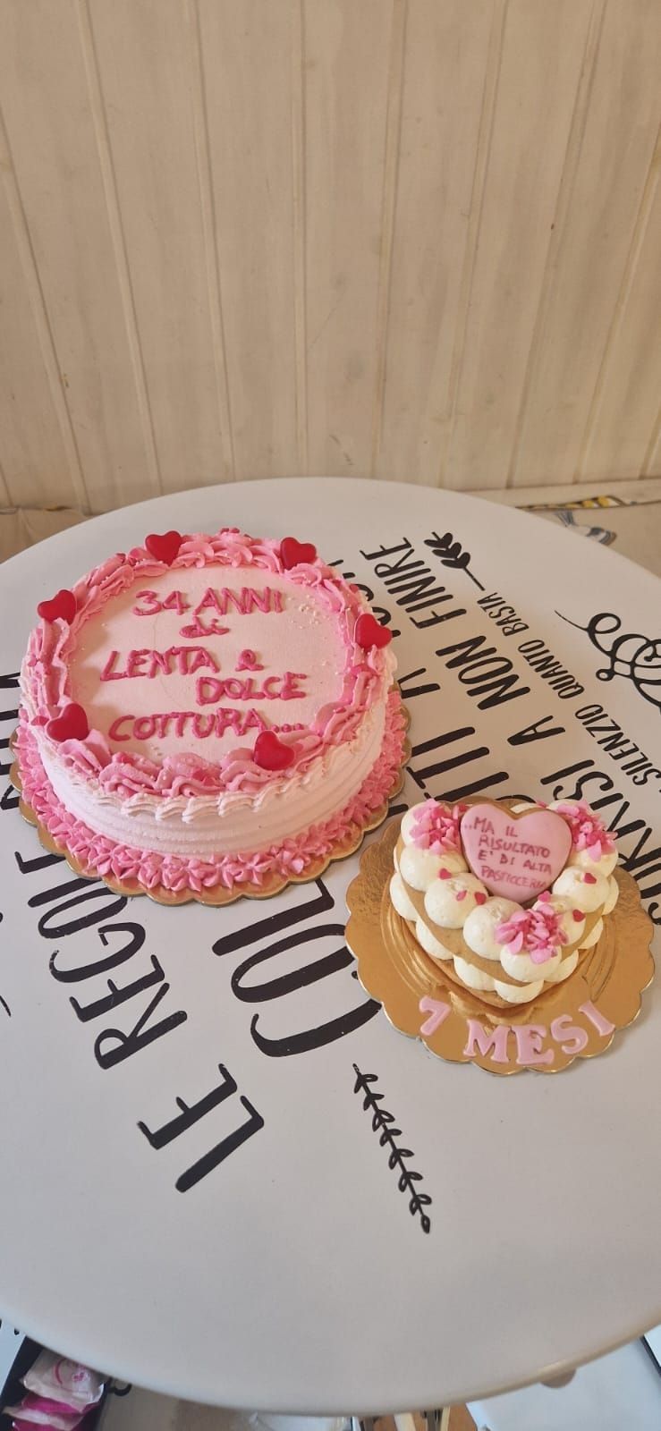 Due torte rosa su un tavolo: una rotonda con una scritta e una a forma di cuore.