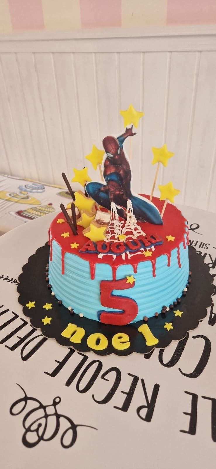 Torta di compleanno di Spider-Man. Torta rossa e blu con una statuina di Spider-Man e il numero 5.