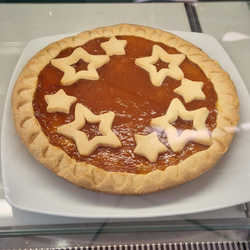 Crostata ai mirtilli con crosta a reticolo su un piatto bianco, circondata da mirtilli e marmellata.