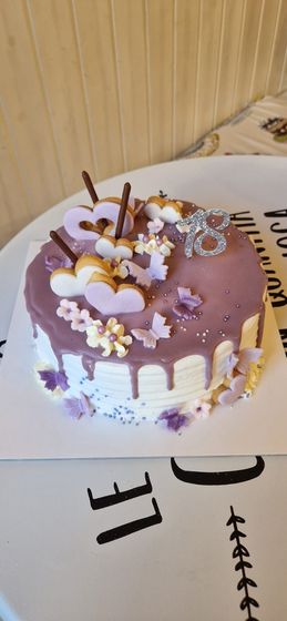 Una torta per il 18° compleanno con glassa viola, decorazioni e un topper con la scritta