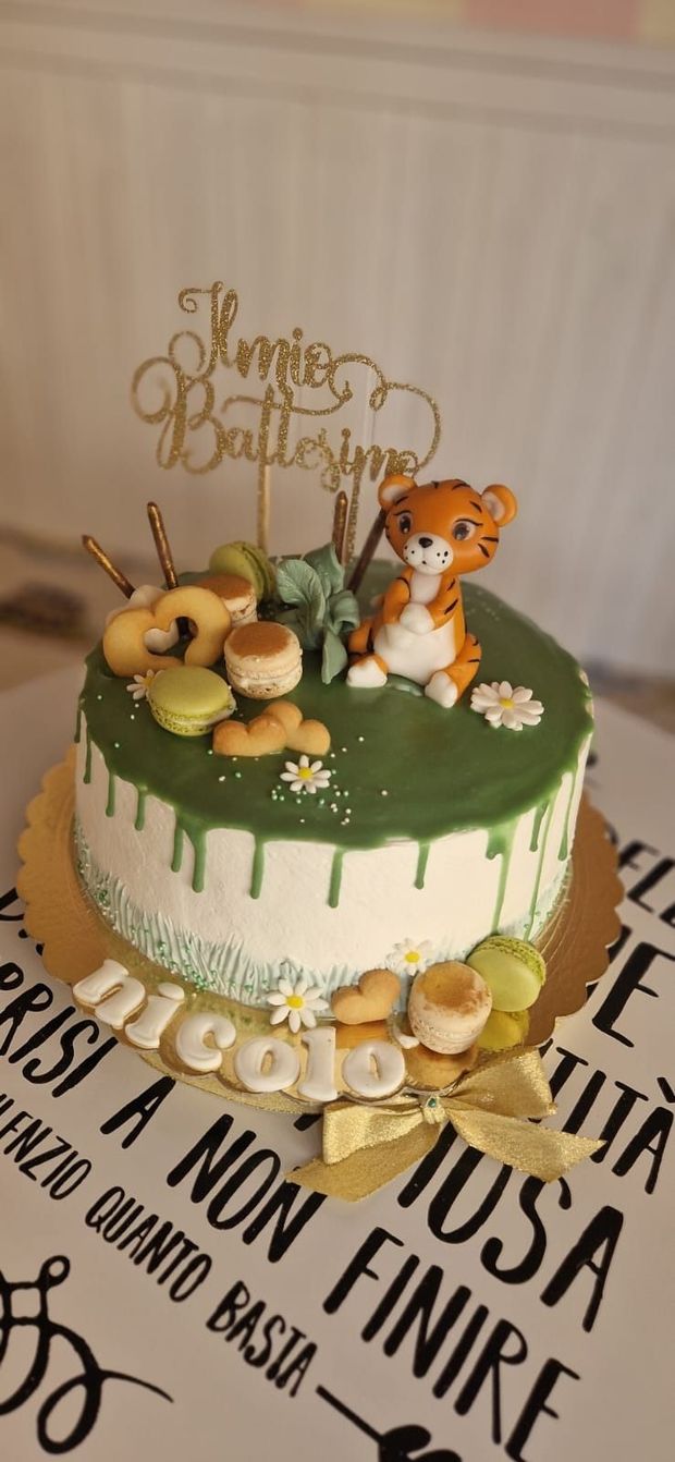 Una torta di compleanno con una statuina di tigre, macaron e il nome 