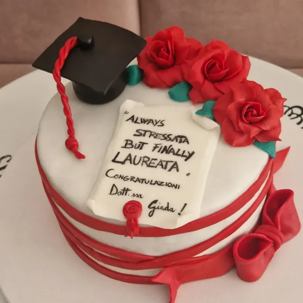 Torta di laurea con rose rosse, tocco e una pergamena.