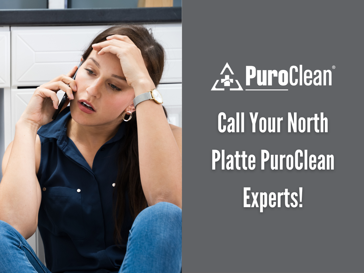 A woman is sitting on the floor talking on a cell phone.