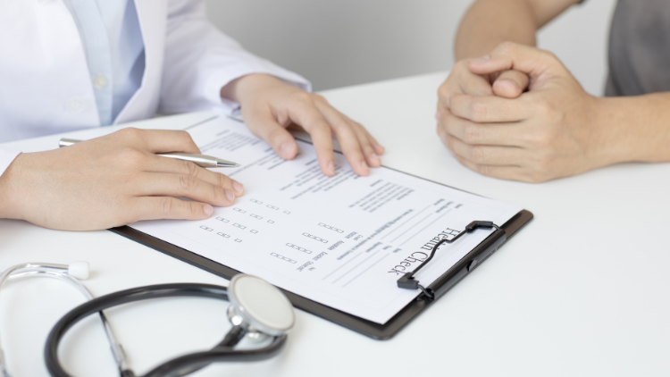 A doctor is talking to a patient while looking at a clipboard