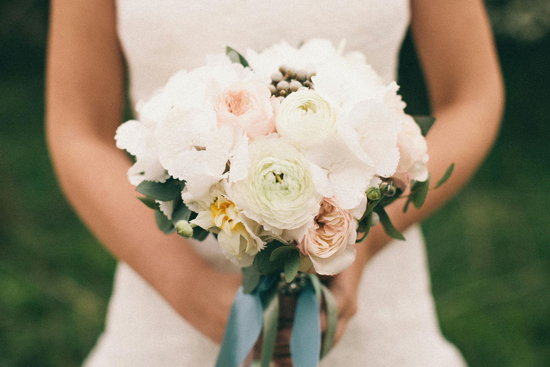 A bride in a white dress is holding a bouquet of flowers