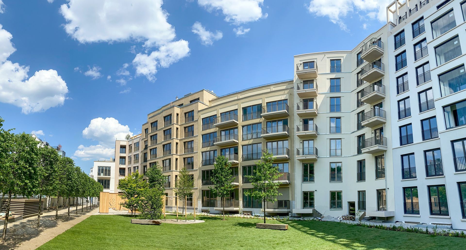 A large apartment building with a lot of windows is surrounded by trees and grass.