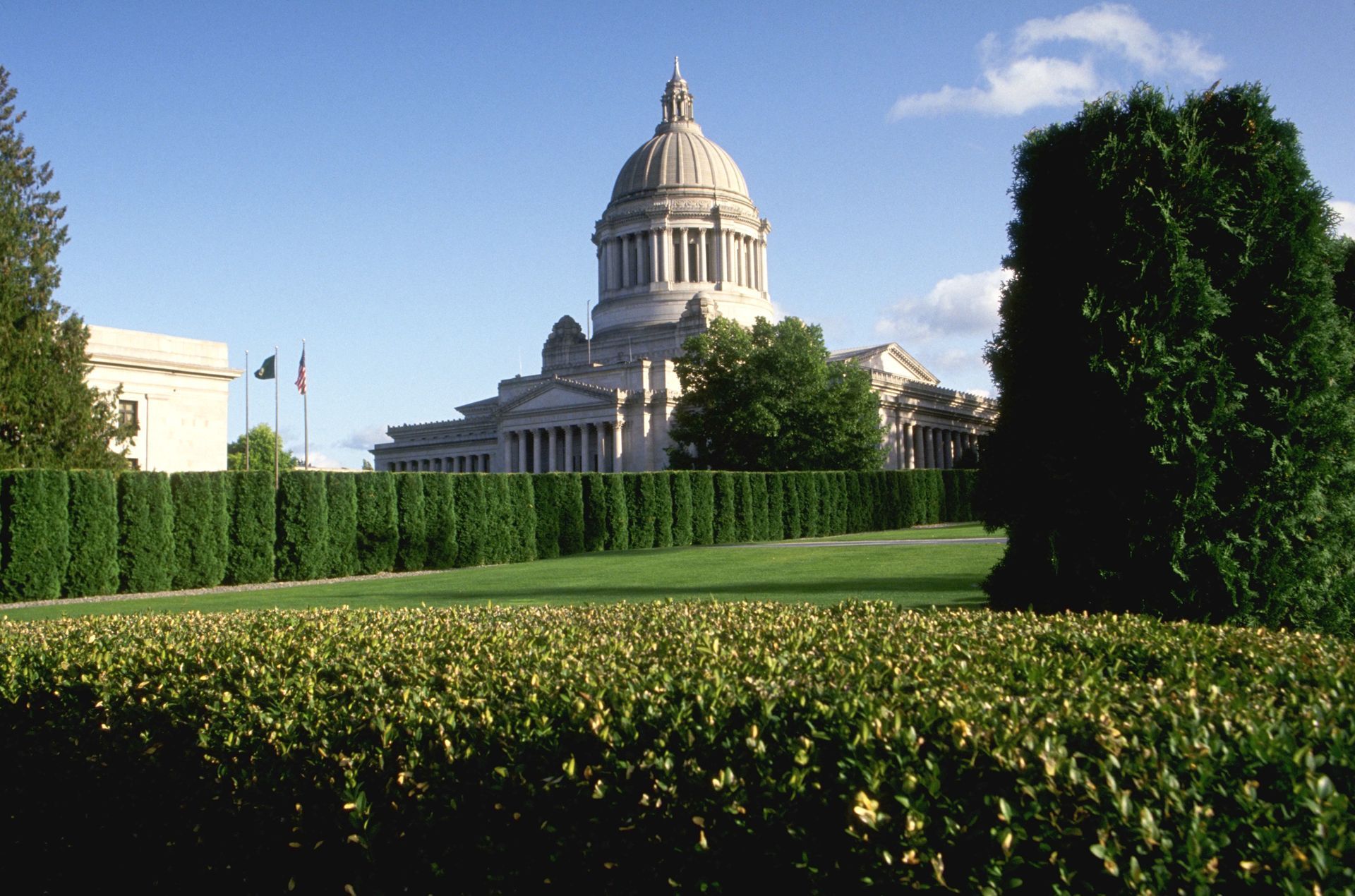 The white house is surrounded by trees and a fence.