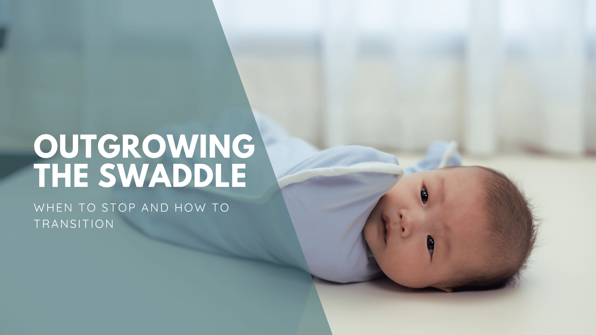 A baby lies on a white surface in a light blue swaddle, looking calm.