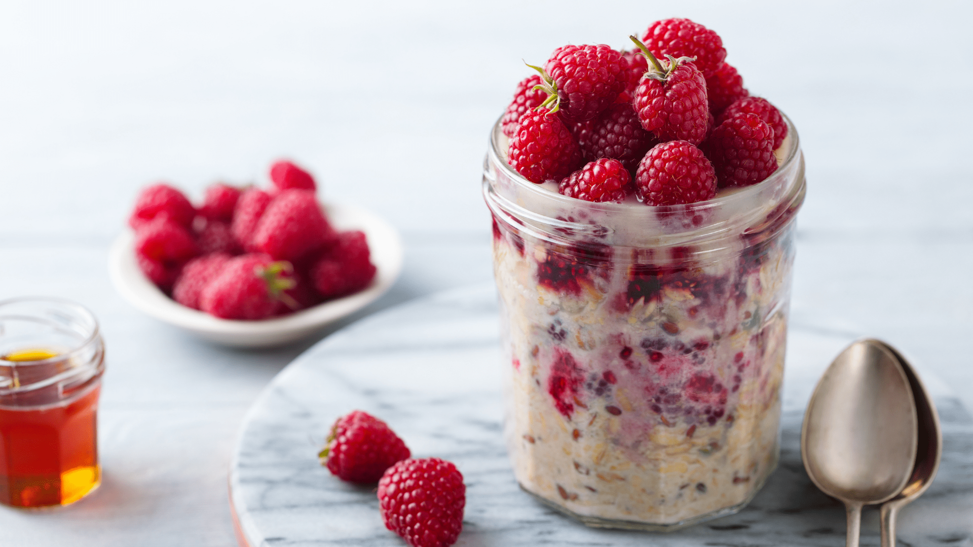 A bowl of raspberry overnight oats topped with fresh raspberries and a sprinkle of chia seeds.