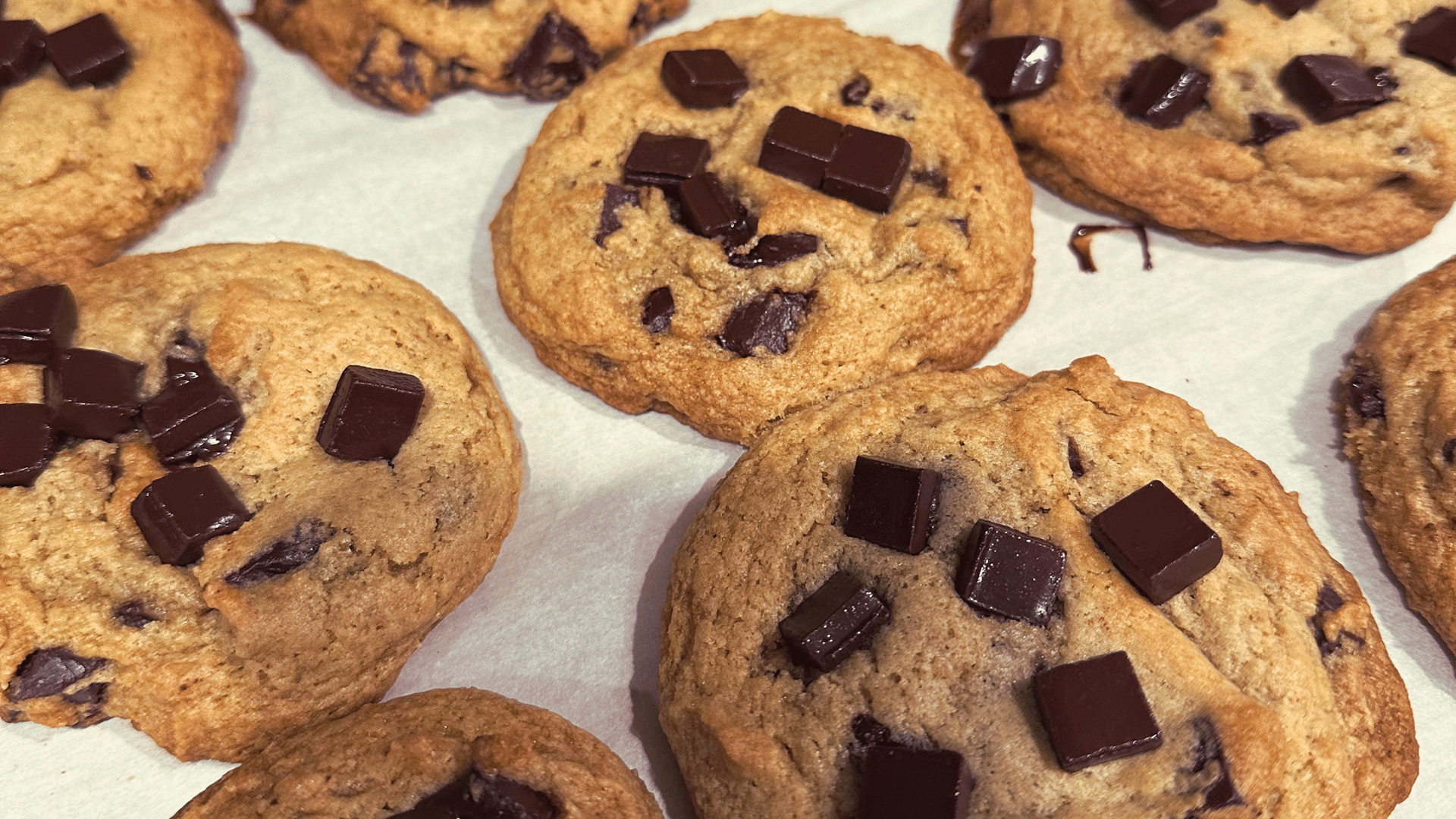 A batch of chocolate chip cookies, showcasing a soft texture and an abundance of chocolate chips.