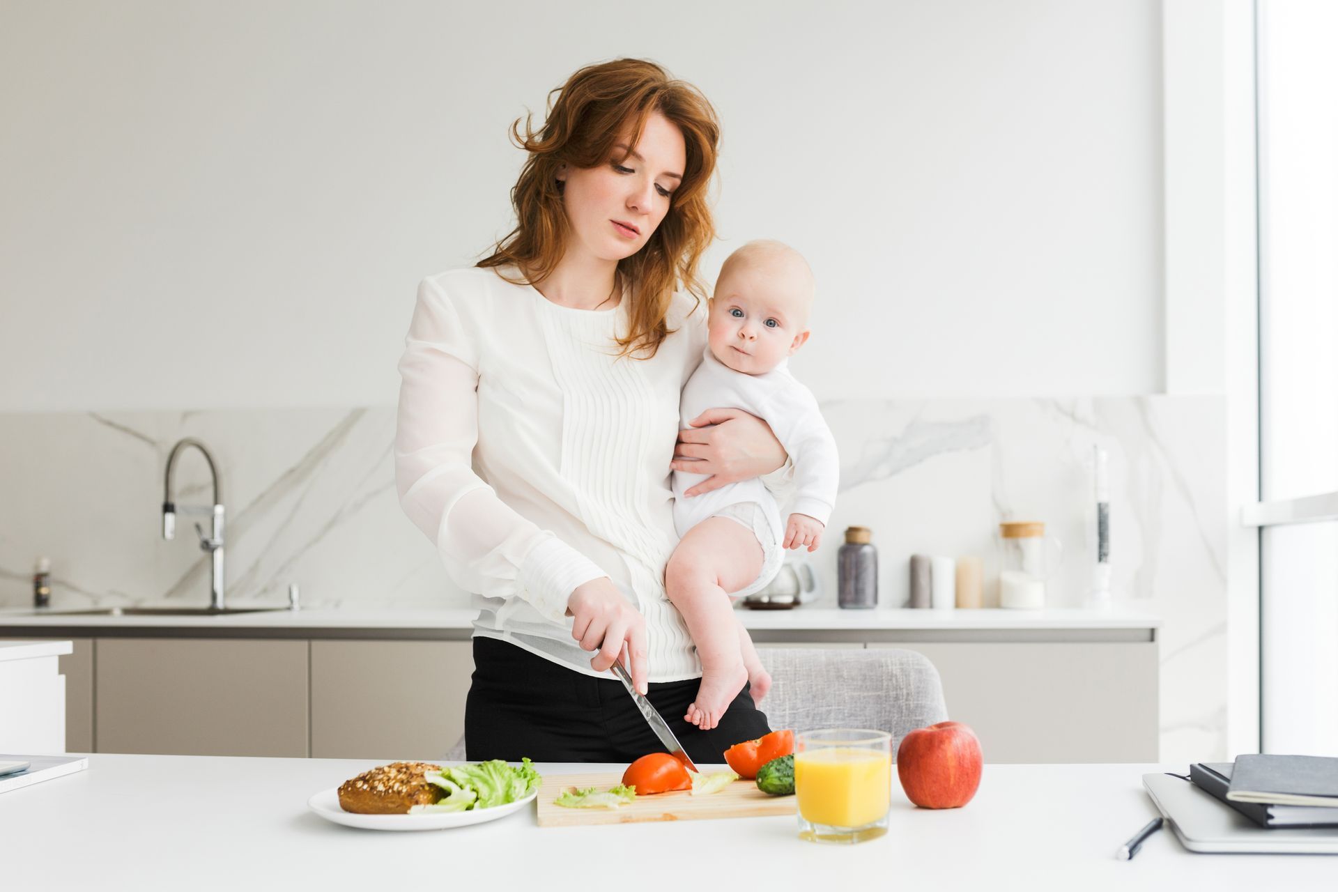 a woman holding her baby and cutting food